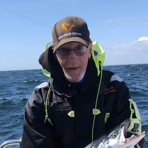 Butiksassistent Preben Hingeberg fra Aarhus Fishing Gear på fisketur i solskinsvejr, iført Savage Gear kasket og med en frisk fangst i hænderne.